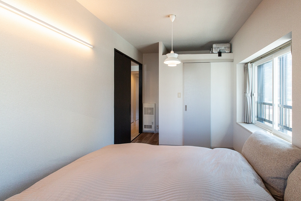 リノベーション後：DAIKOブラケット照明とベージュトーン統一の寝室夜景