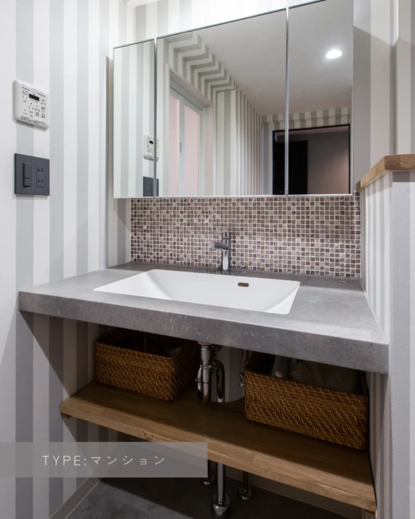 リノベーション後：ストライプクロスと合わせてモザイクタイルを使用したエレガントな雰囲気の洗面台